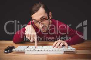 Man wearing eye glasses pointing on computer keyboard