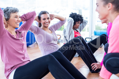 Women exercising on floor with hands behind head