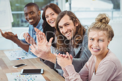 High angle portrait of smiling business people clapping at desk