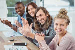 High angle portrait of smiling business people clapping at desk