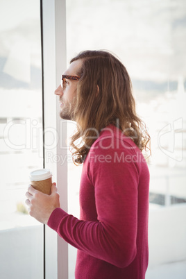 Side view of man holding disposable cup in office