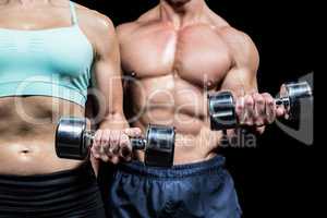 Midsection of woman and man exercising with dumbbells