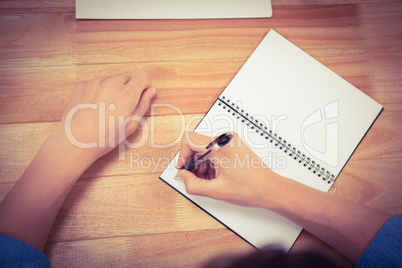 Businessman writing on spiral notebook at desk in office