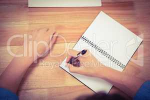 Businessman writing on spiral notebook at desk in office