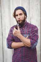 Hipster wearing knitted hat smoking pipe