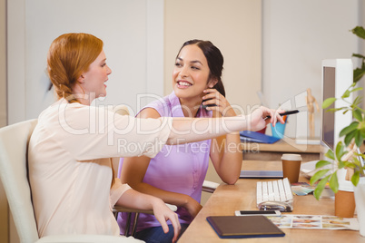 Businesswoman showing something on computer to happy colleague