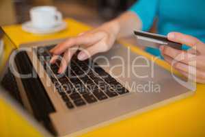 Woman using laptop while holding credit card