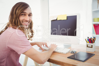 Portrait of happy hipster typing on keyboard in office