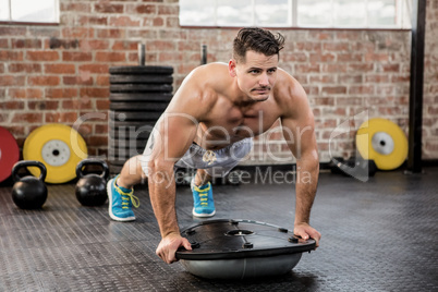 Muscular man doing bosu push ups