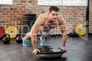 Muscular man doing bosu push ups