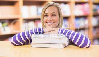 Happy young woman leaning on book at desk