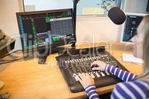 Female radio host in front of screen operating sound mixer