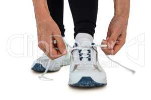 Low section of sporty woman tying shoelace
