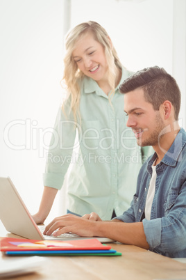 Smiling young man and woman working on laptop