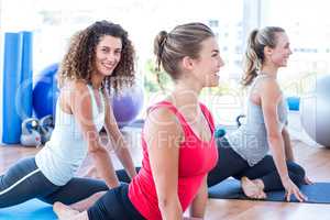Women smiling while doing pigeon posture