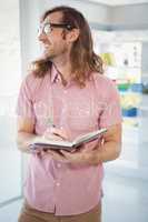 Happy hipster holding book and pen