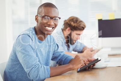 Portrait of happy man wearing eyeglasses while using digital tab