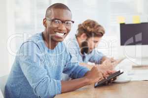 Portrait of happy man wearing eyeglasses while using digital tab