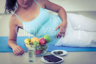 Pregnant woman lying by fruits and chocolates