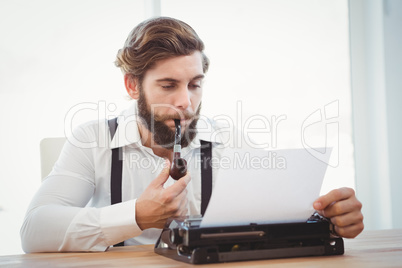 Hipster with smoking pipe working on typewriter