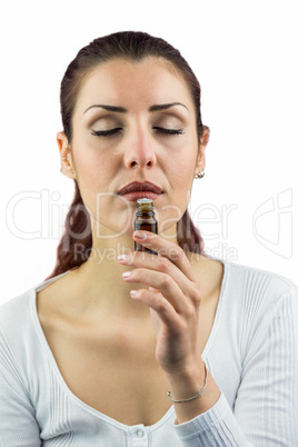 Woman with eyes closed and smelling bottle of medicine