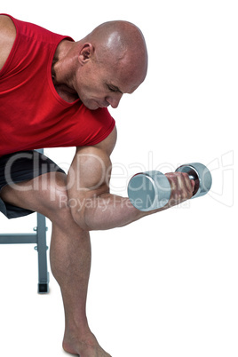 Bald man exercising by lifting dumbbells