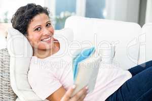 Pregnant woman with book holding coffee