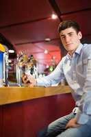 Confident man holding mobile phone at bar counter