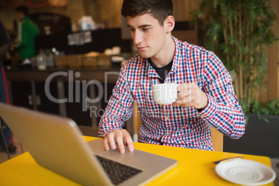 Young man with coffee using laptop