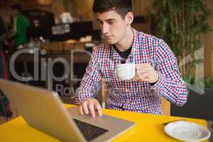 Young man with coffee using laptop