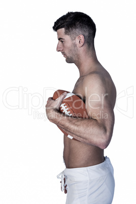 Side view of shirtless man holding ball