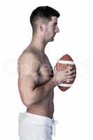 Side view of a shirtless rugby player holding ball