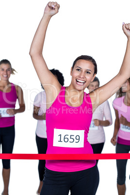 Smiling winner athlete crossing finish line with arms raised