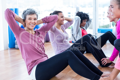 Woman doing sit ups with friends at fitness studio