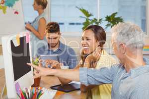 Businessman pointing on computer as female colleague looking at