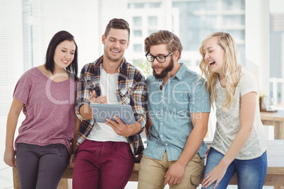 Smiling business people using digital tablet while standing at d