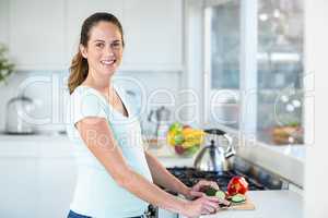 Happy woman cutting cucumber