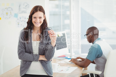 Portrait of smiling businesswoman holding eyeglasses with cowork
