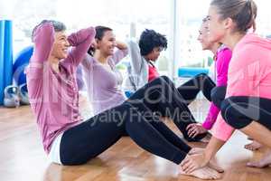 Women helping friends to do sit ups