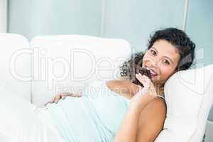 Happy pregnant woman eating chocolate bar