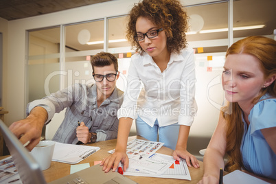 Businessman pointing on laptop as female colleagues looking at i