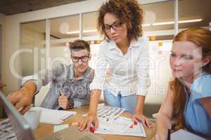 Businessman pointing on laptop as female colleagues looking at i