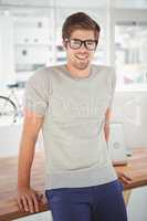 Happy hipster wearing eye glasses leaning at desk