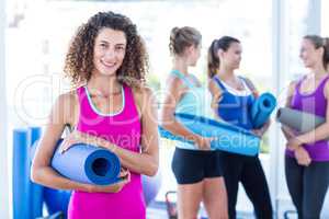 Portrait of a woman smiling while holding exercise mat