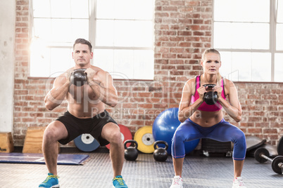 muscular serious couple with kettlebells