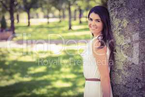 Portrait of cheerful woman leaning on tree