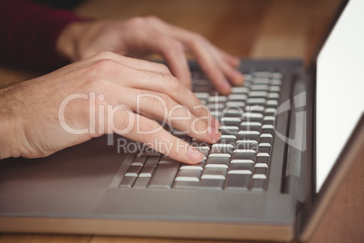 Cropped hand of man working on laptop