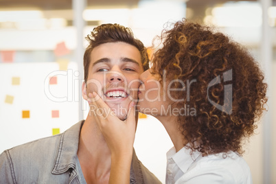 Woman with curly hair kissing businessman