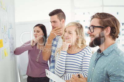 Thoughtful business people pointing at wall with sticky notes an