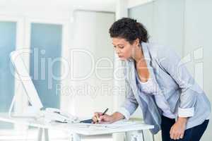 Businesswoman writing on document at desk